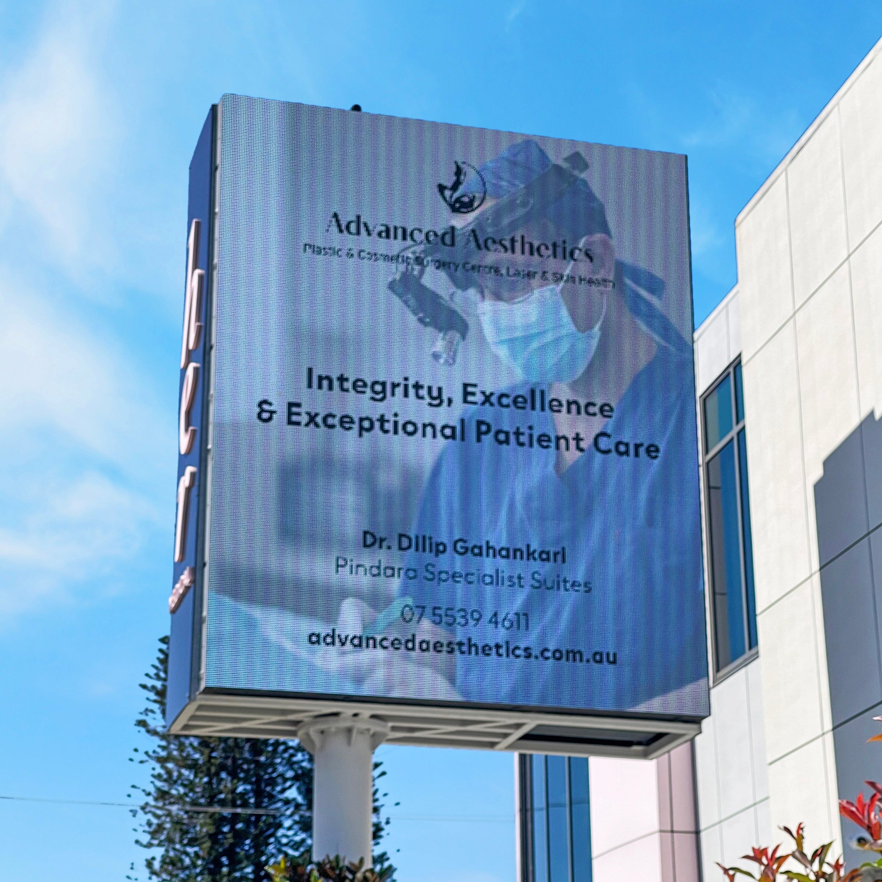 Billboard for Advanced Aesthetics with a doctor's image and text on a building.