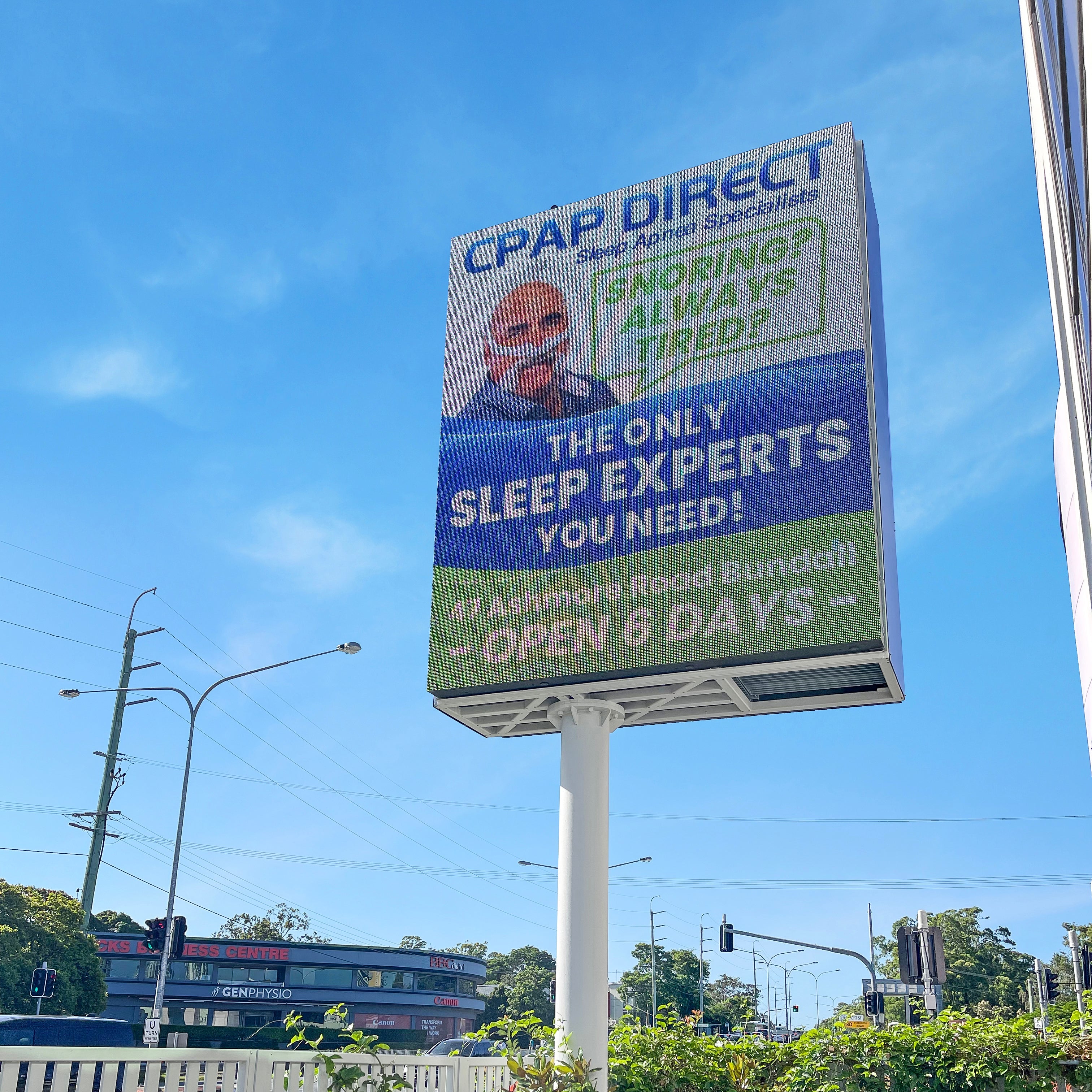 Billboard advertisement for CPAP Direct against a blue sky with trees and a car in the foreground.
