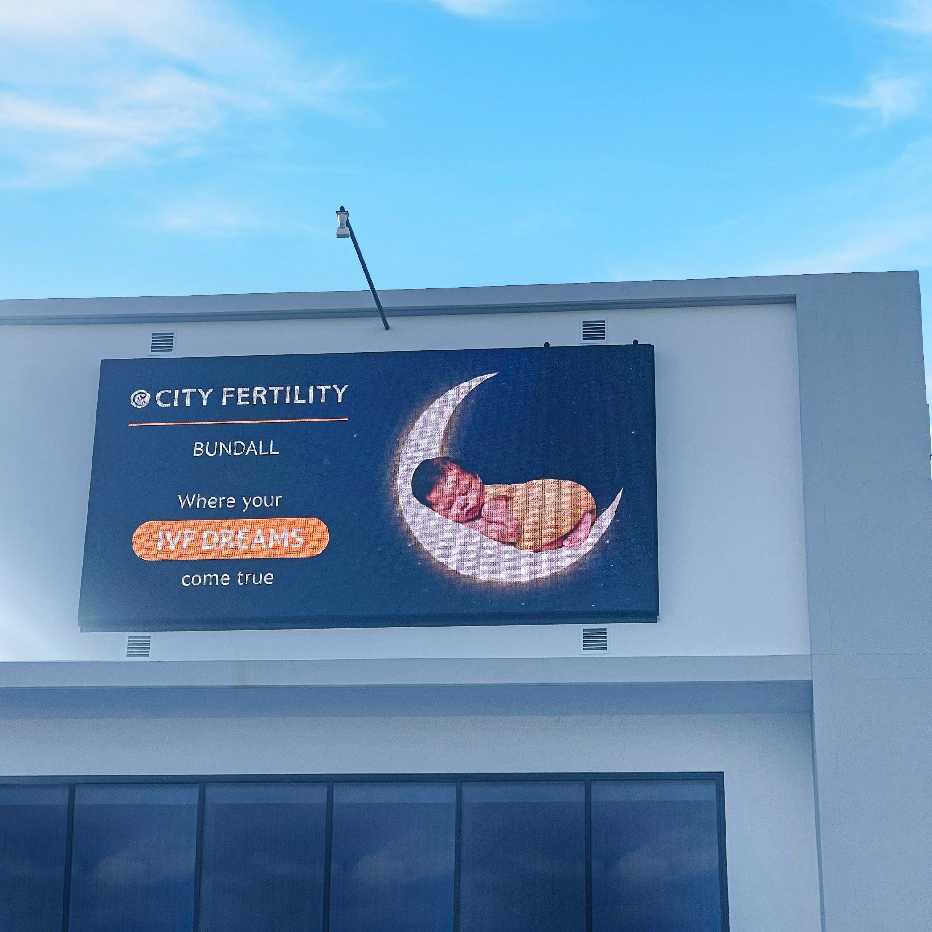 Billboard for City Fertility Bundall with a baby illustration on a building.