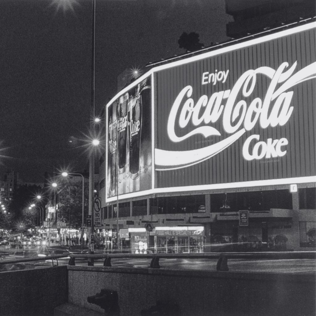 Coca-Cola billboard at night with city lights in the background