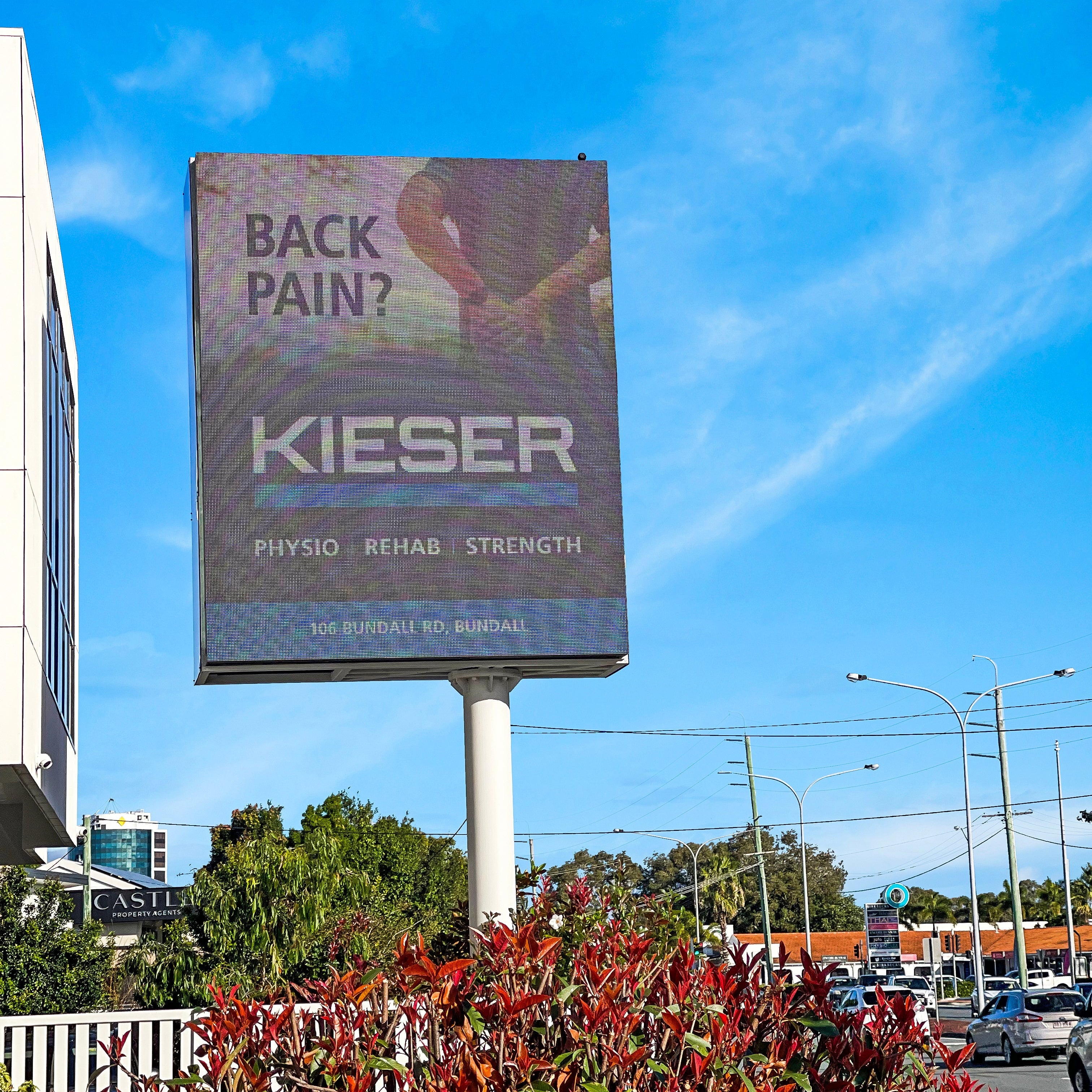 Billboard advertising Kieser physio rehab strength against a blue sky with clouds. Gold Coast Billboards Customer Slide Kieser Her Medical location